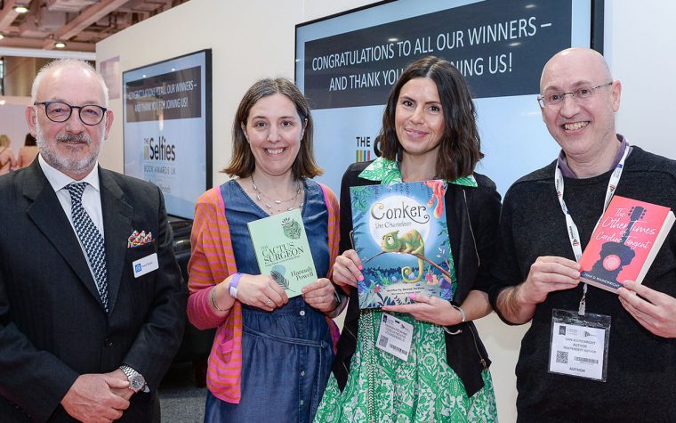 Four people standing together with three holding books at London Book Fair.