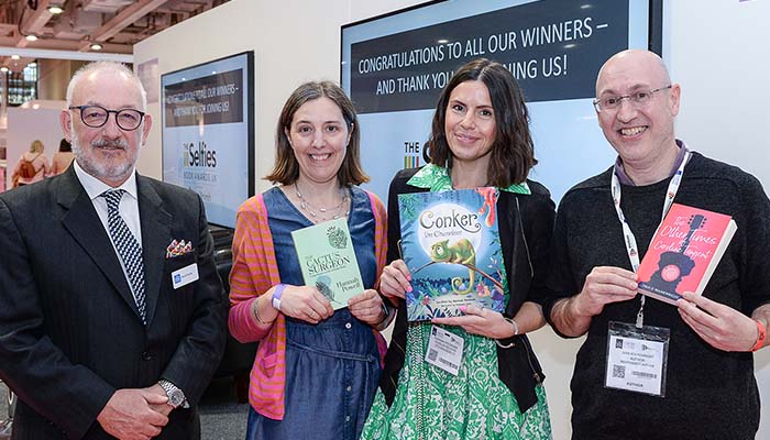 Four people standing together with three holding books at London Book Fair.